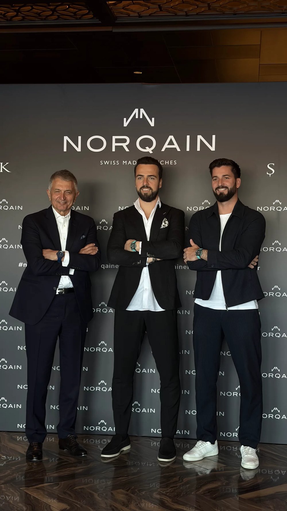 NORQAIN panosunun önünde üç kişi